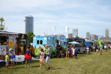 A row of food trucks in park for independence day with crowd of people in front - July 4,2016,...
