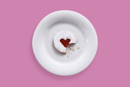 Sweet pastry heart with jam and icing sugar on a plateの写真素材