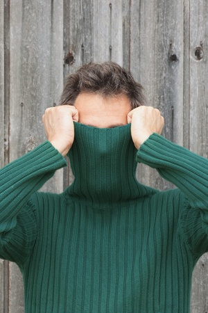 Man pulling turtleneck over his faceの写真素材