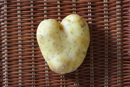 Heart shaped potato on brown rattan backgroundの写真素材