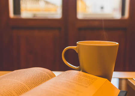 Porcelain coffee cup and book in front of the window giving it the sunの写真素材