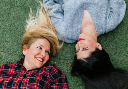 Blonde and brunette friends looking at each other and smiling