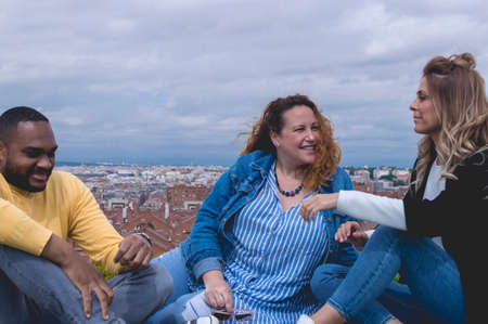 Happy interracial friends sitting in a park talking and laughingの写真素材