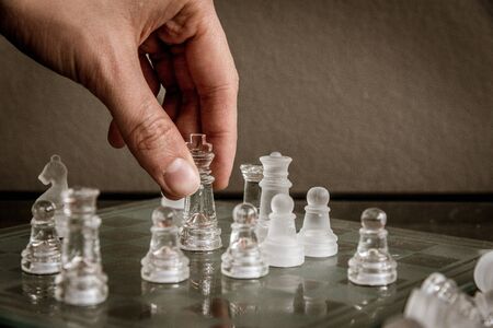 Hand moving the queen on the glass chessboardの写真素材