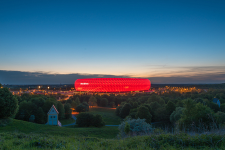MUNICH, GERMANY - APRIL 29, 2018: Aerial view of Allianz Arena, the football stadium of FC Bayern, illuminated in red at the dusk from Frtttmanninger Bergのeditorial素材