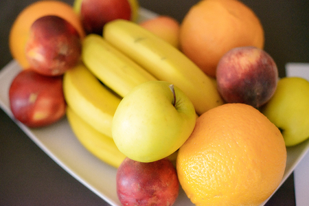 Uncut fruit platter with bananas, nectarines, apples and oranges. Plate of fresh fruit suitable for a healthy and organic diet, for children and adults alike.の写真素材