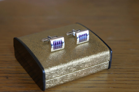 A pair of silver, platinum or white gold cuff links with blue enamel positioned on an elegant golden...