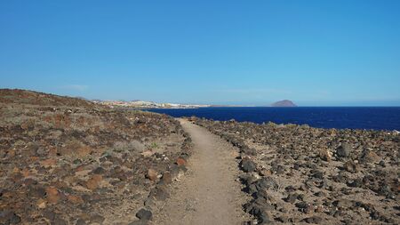 Hiking trail nearby Atlantic through the arid volcanic landscape of the island, views from Montana Amarilla towards Marina San Miguel, outdoor natural attraction in Tenerife, Canary Islands, Spainの写真素材