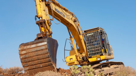 Los Abrigos, Tenerife, Canary Islands, Spain - February 27, 2019: Komatsu mini excavator, heavy machinery with extensive uses performing leveling and terracing, landscaping work for a path constructionのeditorial素材