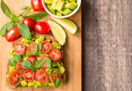 Toast with avocado, tomatoes and basil on rustic wooden backgroundの写真素材