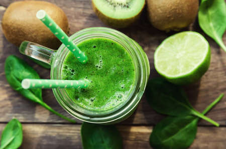 Fresh green smoothie with kiwi, lime and spinach on rustic wooden background. Top view. Selective focus.の写真素材