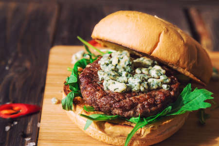 Fresh burger with blue cheese and arugula on rustic wooden backgroundの写真素材