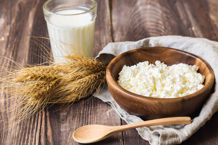 Cottage cheese, milk and ears of wheat on rustic wooden background. Dairy products for jewish holiday Shavuot.の写真素材