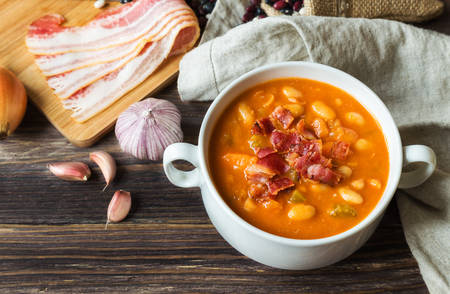 Homemade bean soup in white bowl on rustic wooden background with ingredients.の写真素材