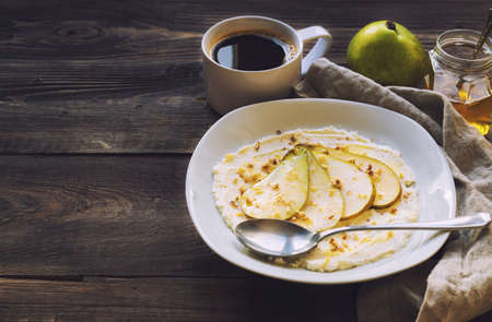 Ricotta cheese with pear,crushed walnuts and honey on rustic wooden background. Healthy breakfast.の写真素材