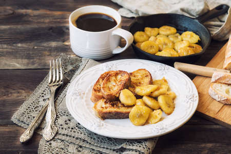 French toasts with fried bananas for breakfast on rustic wooden backgroundの写真素材