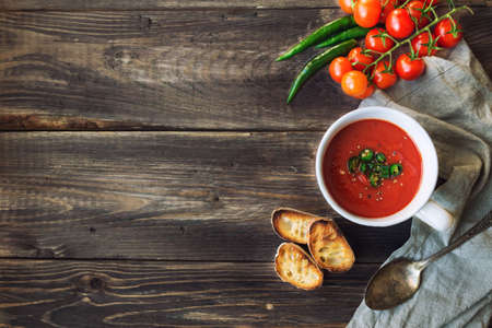 Tomato soup with jalapeno pepper and toasted bread on rustic wooden background. Top view.の写真素材