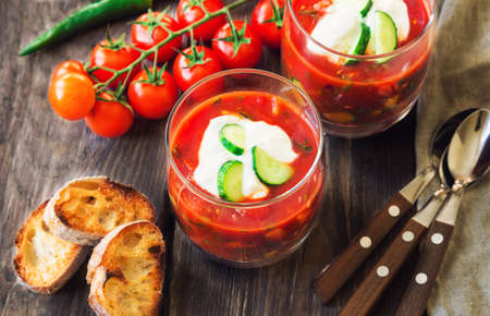 Homemade tomato soup gazpacho in glasses with toasted bread on rustic wooden background. Healthy food. Spanish cuisine.の写真素材