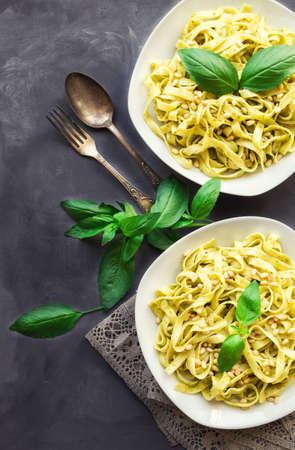 Fettuccine pasta with pesto sauce, basil and pine nuts on concrete background. Italian cuisine. Top viewの写真素材