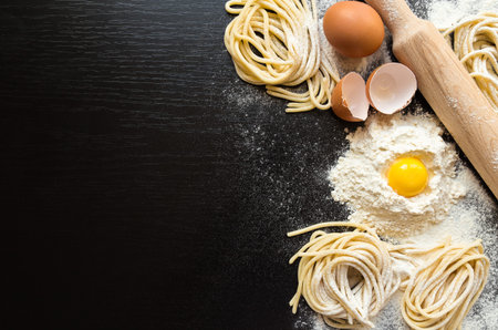Raw homemade pasta with ingredients on black background. Top view.