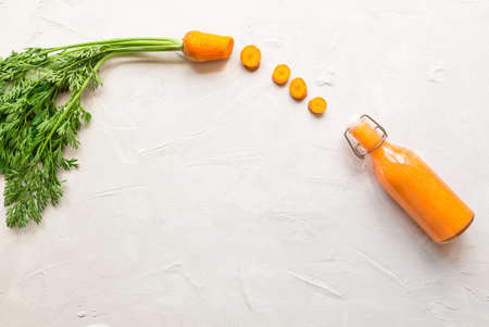 Fresh carrot smoothie in bottle on light concrete background. Top view. Copy space area.の写真素材