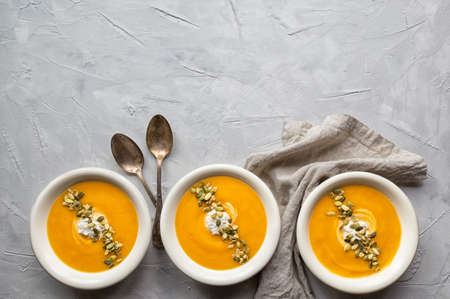 Fresh homemade pumpkin soup with ricotta cheese and seeds on gray concrete background. Top view. Copy space area.の写真素材
