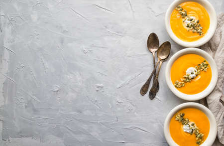 Fresh homemade pumpkin soup with ricotta cheese and seeds on gray concrete background. Top view. Copy space area.の写真素材