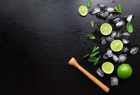Limes, mint leaves and ice cubes on blackの写真素材