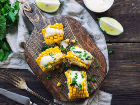 Fresh baked corn cobs with aioli sauce and cilantro on rustic woodenの写真素材