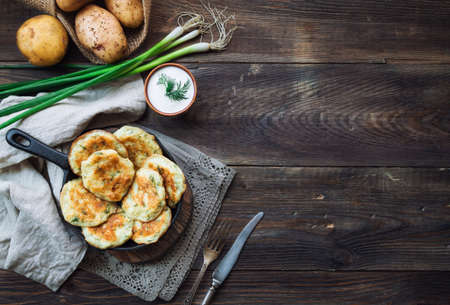Fresh homemade pan-fried potato pancakes latkes in iron skillet on rustic woodenの写真素材