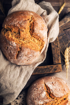 Homemade rye bread with coriander seeds on rustic wooden background. Top view.