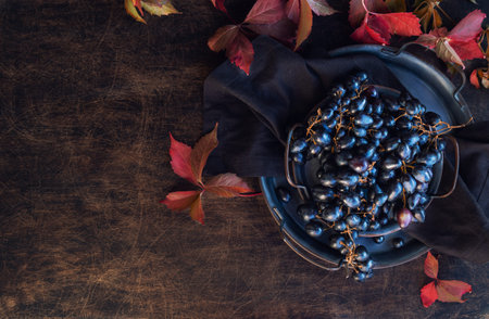 Fresh organic black grapes in vintage tray on rustic plywood background. Top view. Space for text.