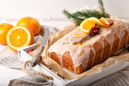 Christmas orange cake with cranberries and sugar icing on rustic wooden background. Holiday...