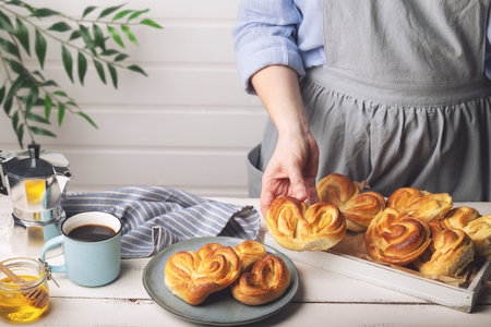 Homemade sweet buns in woman's hand. Serving breakfast at white rustic kitchen.の写真素材
