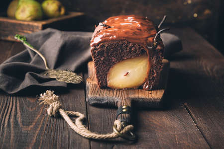Homemade chocolate cake with pear at rustic wooden background. Brownie with fudge.の写真素材