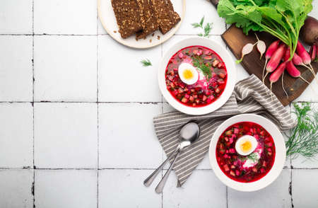 Summer cold beetroot soup with sour cream and egg on white tile background. Russian cuisine. Top view. Space for text.の写真素材