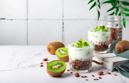 Homemade granola parfait with kiwi fruit in glasses. Healthy breakfast. Space for text.の写真素材