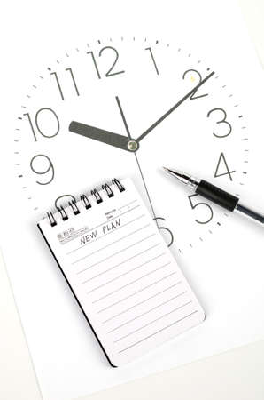 Clock face and notepad with penの写真素材