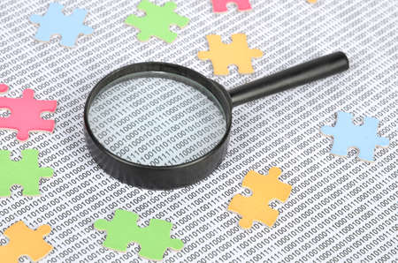 Puzzle and binary code with magnifierの写真素材
