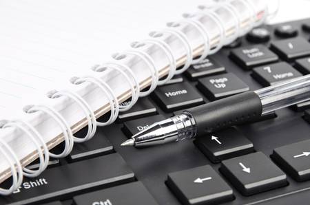 Notepad and pen on keyboardの写真素材