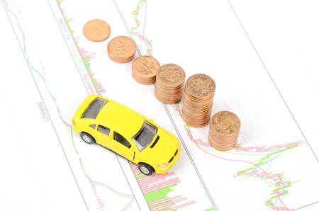 Toy car and coins on financial graphの写真素材