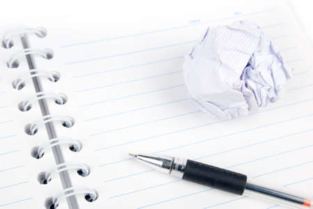 Crumpled paper ball and notepad with penの写真素材