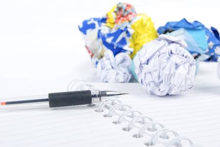 Crumpled paper ball and notepad with penの写真素材
