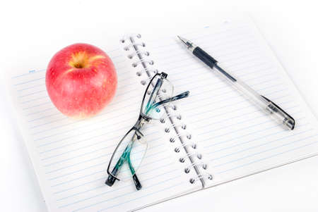 Apple,glasses and pen on notepadの写真素材
