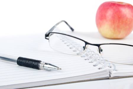 Apple,glasses and pen on notepadの写真素材