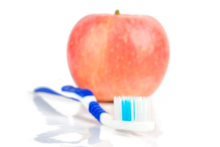 Apple and toothbrush on white backgroundの写真素材