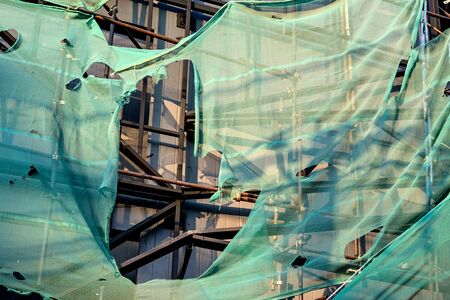 building under construction wrapped in a green net for safetyの写真素材
