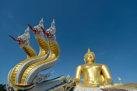 golden budha thailand with blue sky at wat muang thailandの写真素材