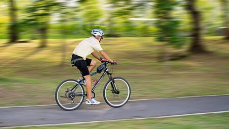 Uncle bicycles to exercise in the park.の写真素材