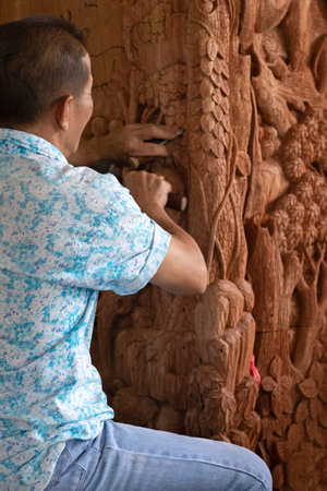 carpenter carving wooden pillars in a temple in Thailandの写真素材
